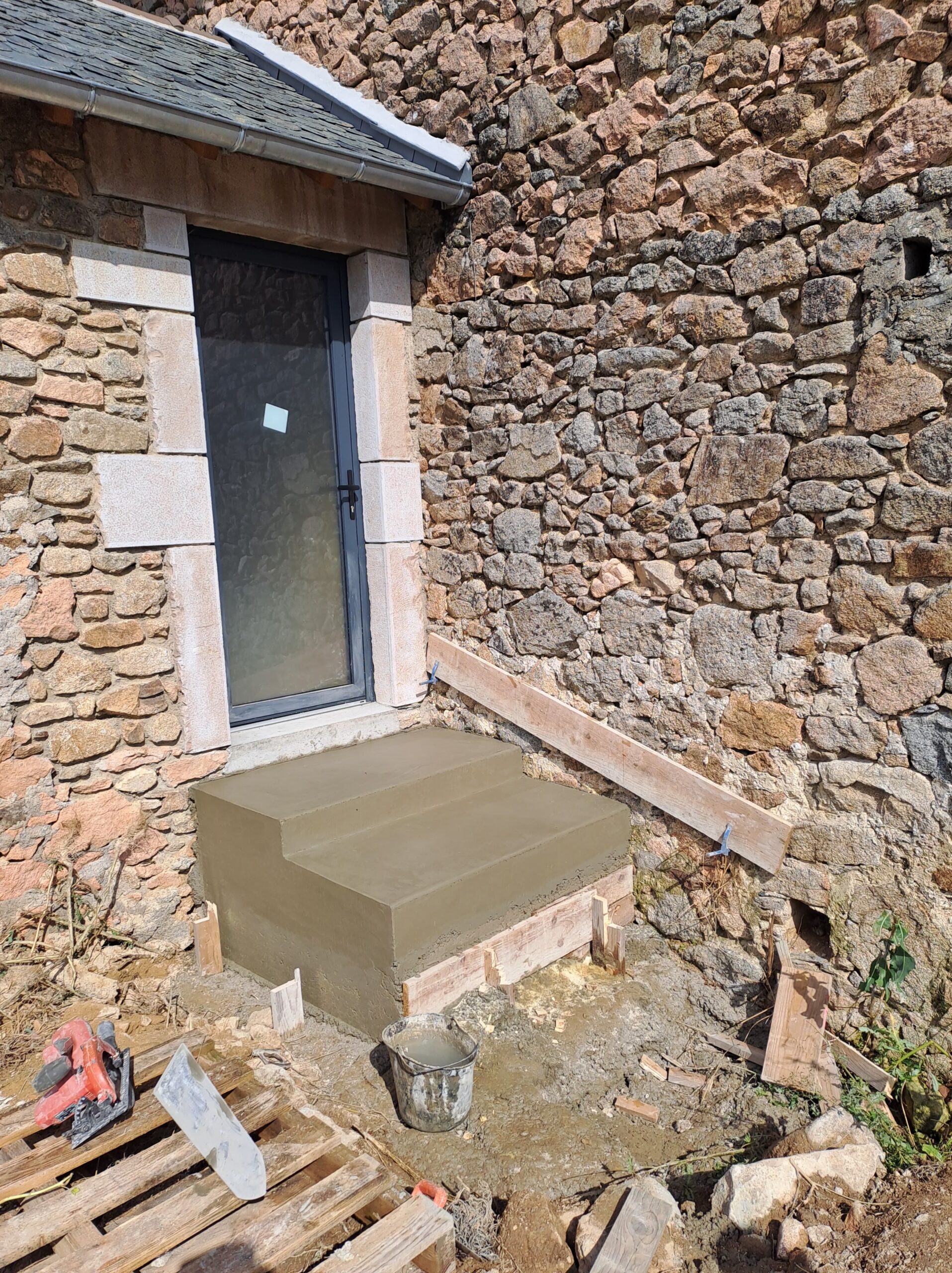 Perron en béton frais devant façade en pierre, chantier mobilier-design-pierre-aveyron en Aveyron