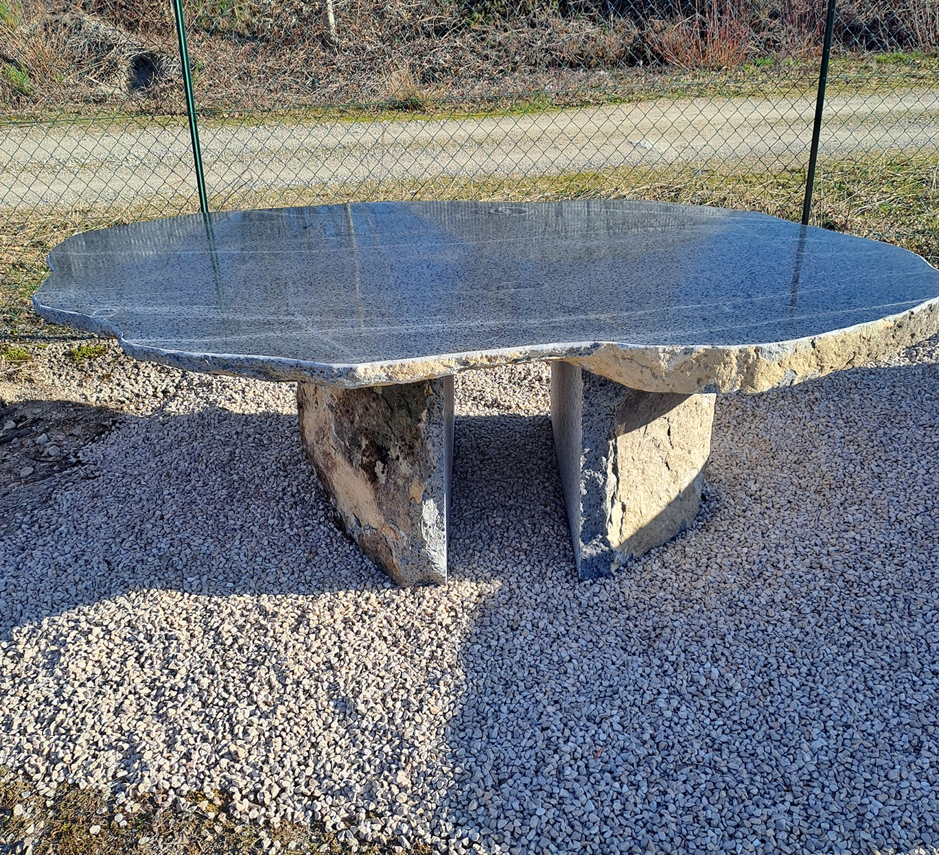 Table de jardin en pierre brute mobilier-design-pierre-aveyron sur gravier clair en extérieur rural Aveyron